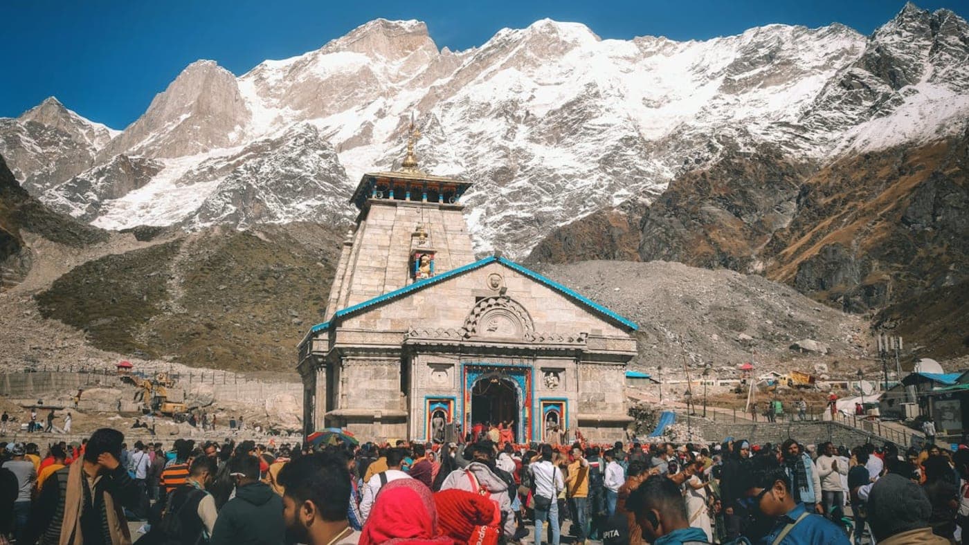 Pilgrims gathered at Kedarnath Temple with snow covered Himalayan mountains during the sacred Divya Char Dham Yatra.