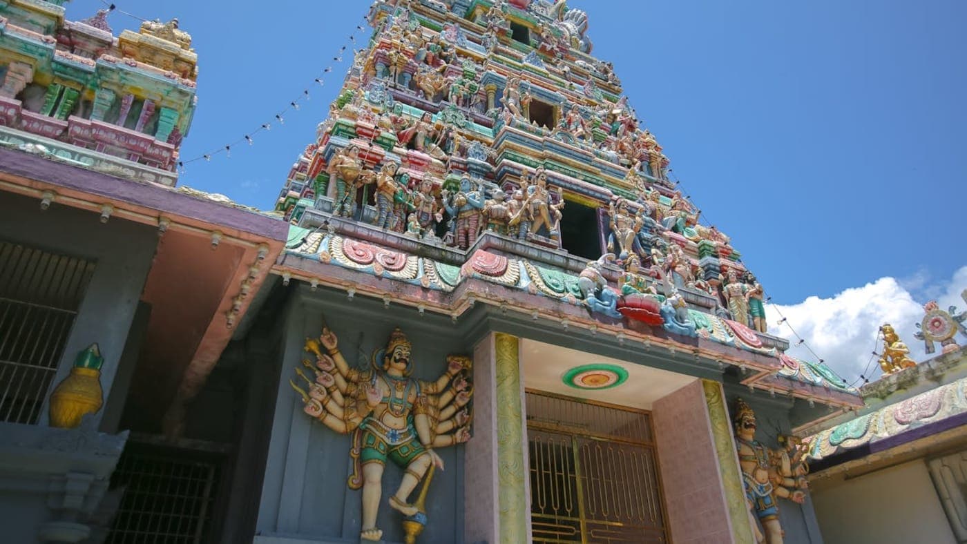 Colorful South Indian temple gopuram with intricate sculptures under clear blue sky in Tamil Nadu.