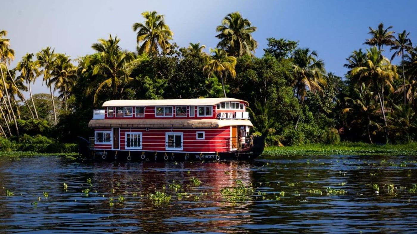 Traditional Kerala houseboat cruising through scenic backwaters surrounded by lush coconut palms.