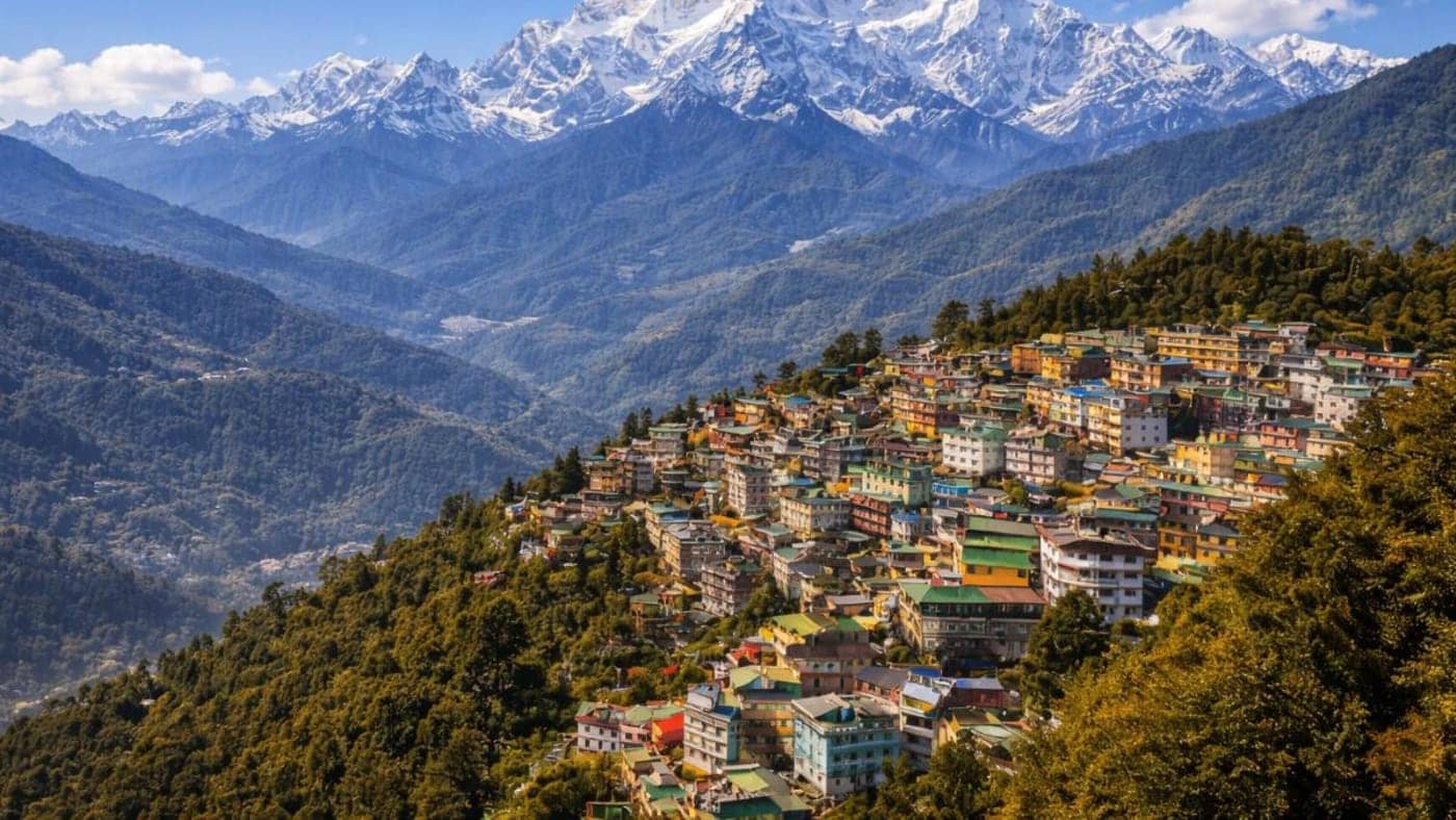 Colorful hillside town overlooking deep valleys with the snow-covered Kanchenjunga mountain range in the background, Sikkim.