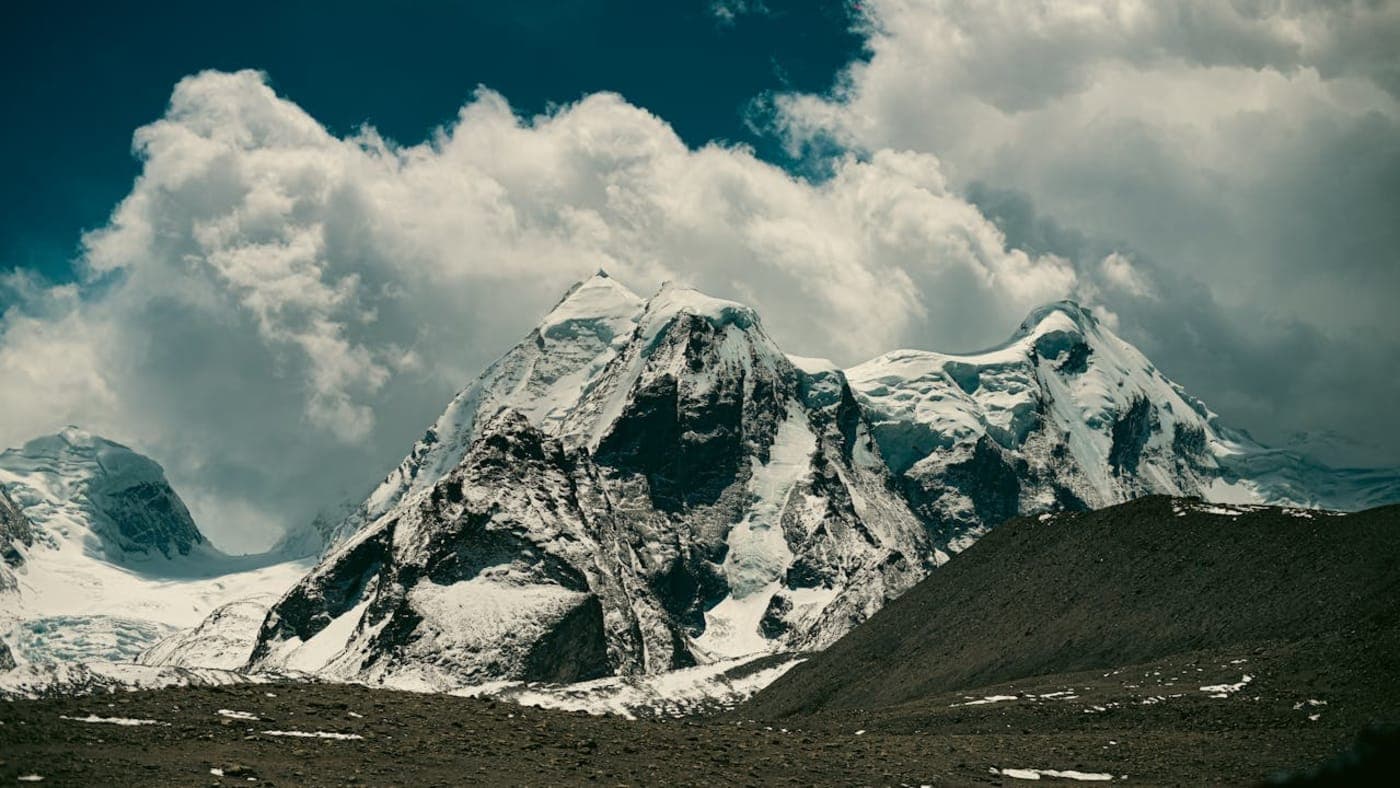 Tourists viewing a massive multi-tier waterfall cascading down lush green mountains with a river flowing below in Sikkim.
