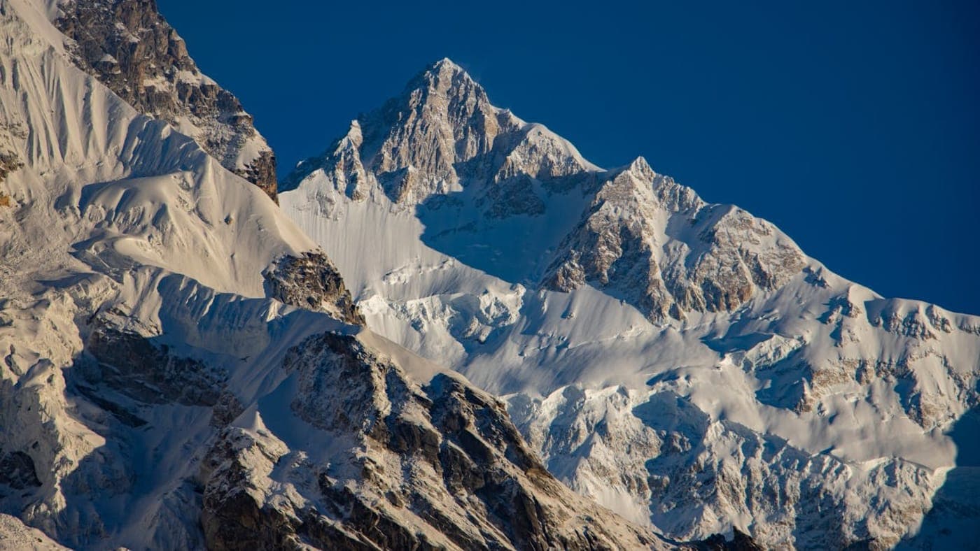 Snow-covered Himalayan peaks in Sikkim with sharp ridges and clear blue sky over a high altitude landscape