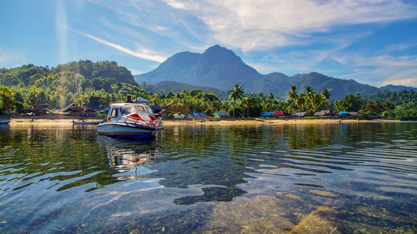 Traditional wooden houses and a longtail boat in a floating market village in Thailand.