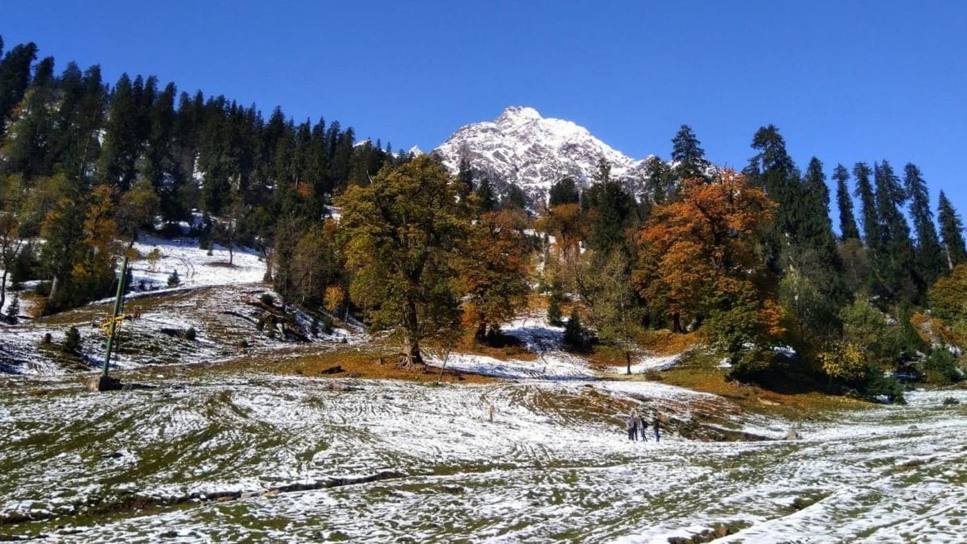 Snow covered Himalayan mountains and rocky valley landscape near Shimla Manali with travelers exploring scenic winter terrain.